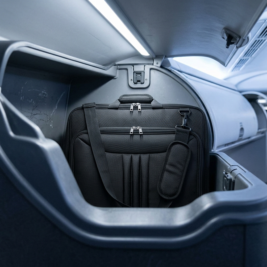 Folded garment bag lying flat inside an aircraft overhead bin
