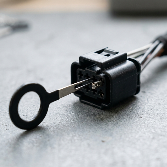 Macro of a removal key inserted into a connector housing beside a seated terminal