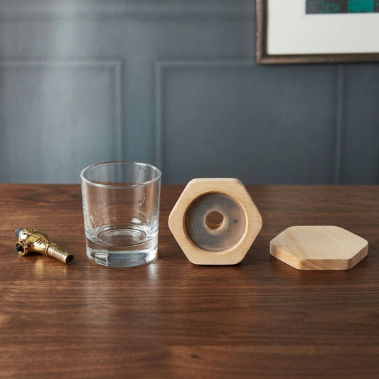 Cocktail and whiskey smoker kit pieces laid out on a walnut bar counter