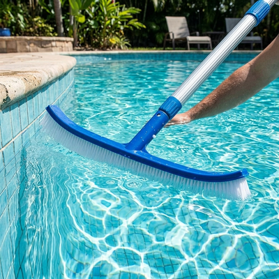 Pool brush on telescopic pole cleaning the wall of a backyard pool