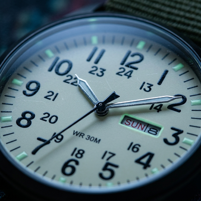 Macro close-up of cream field watch dial with day date window