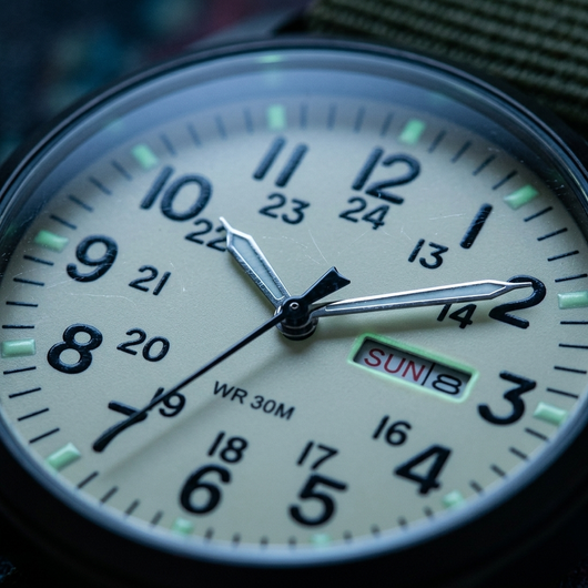 Macro close-up of cream field watch dial with day date window