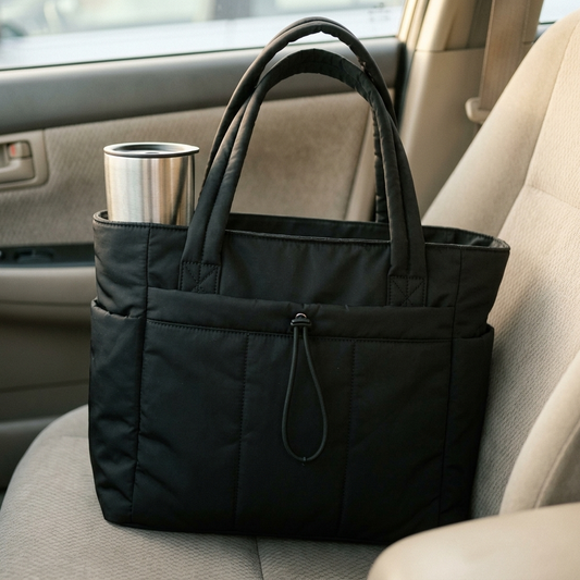 Black quilted puffer tote on a car seat with a tumbler upright in the cup holder pocket