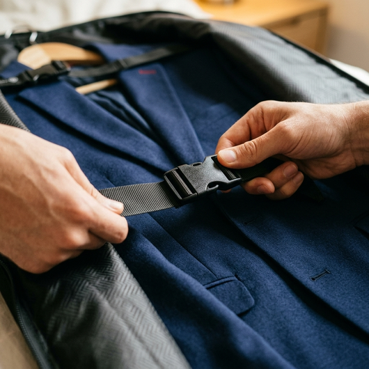 Close up of an interior tie-down strap being pulled tight over a suit jacket