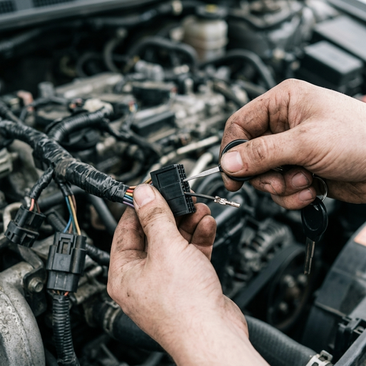 Releasing a pin from a harness connector in an engine bay