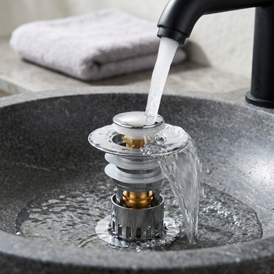 Chrome sink stopper open and draining in a dark stone vessel basin