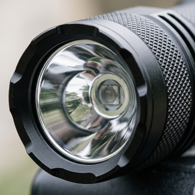 Close up of the bezel, reflector, and knurled body of the black pocket flashlight