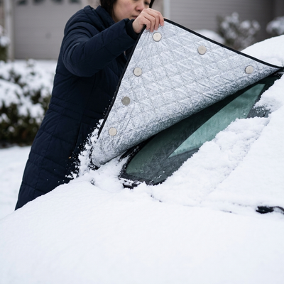 Lifting the snow cover off a windshield with snow sliding away and clean glass beneath