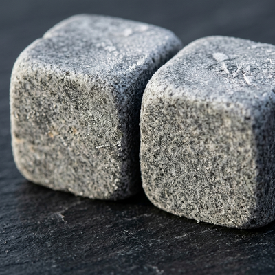 Close detail of two frosted soapstone chilling stones on a slate surface